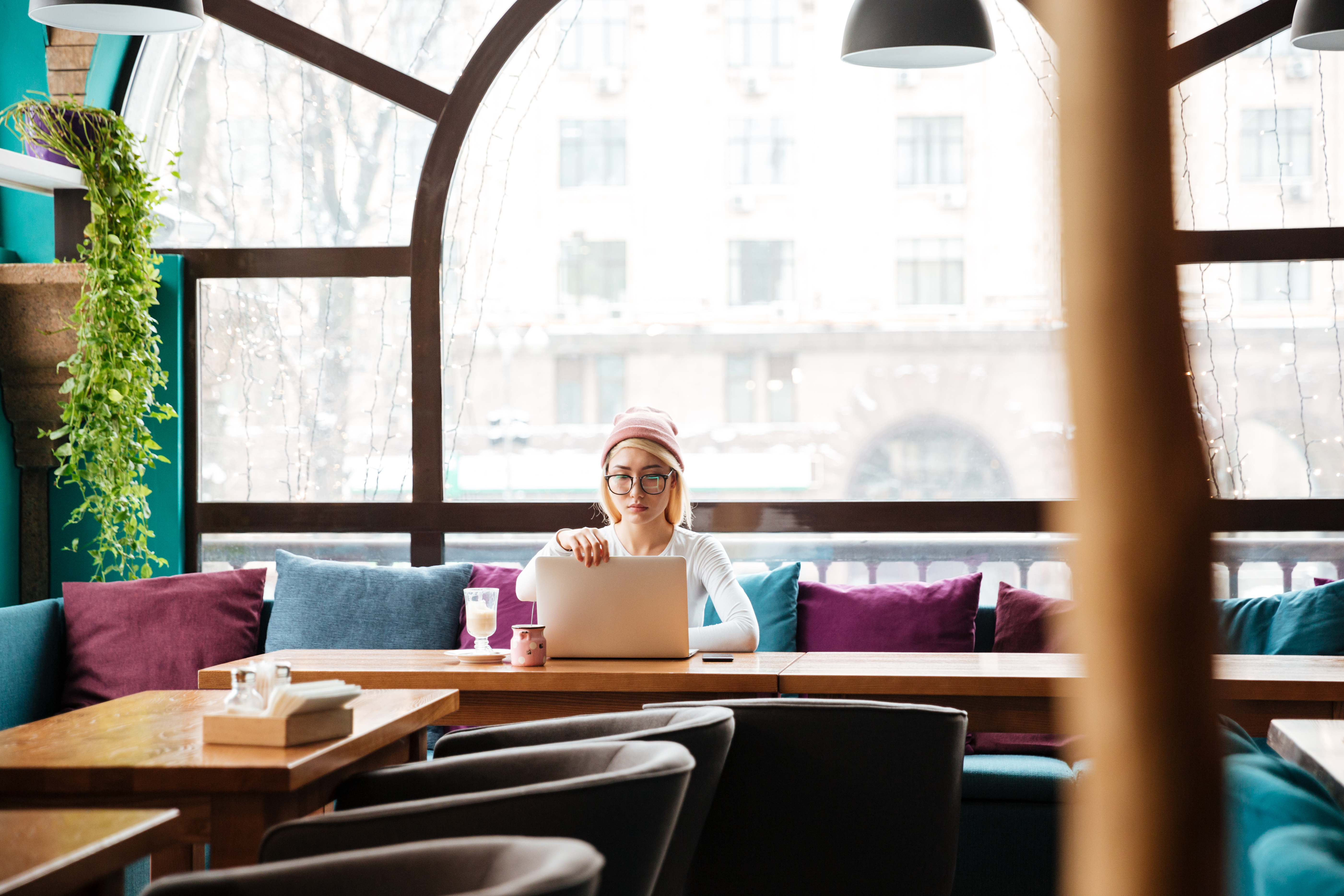Serious young woman sitting and using laptop in cafe