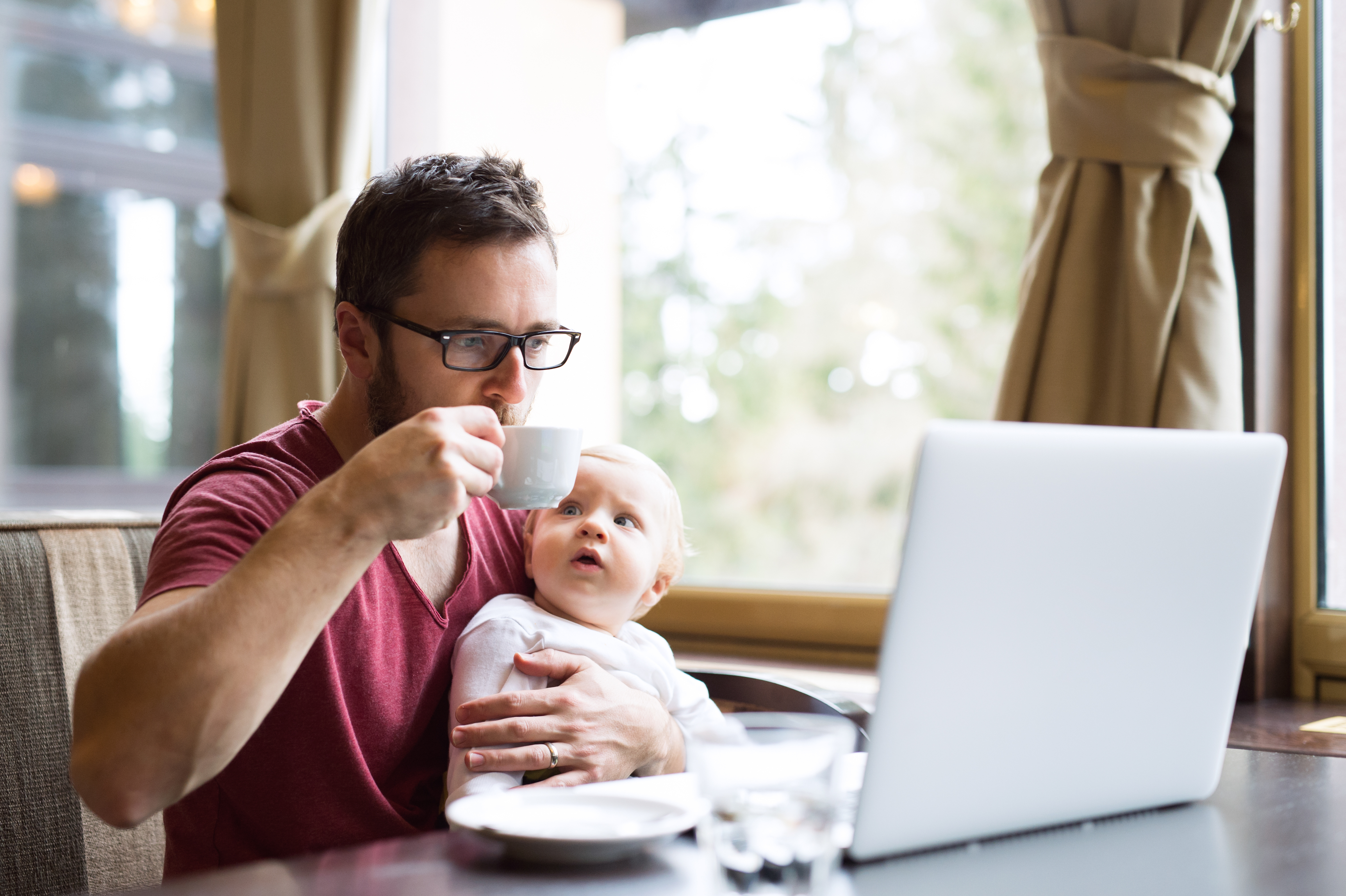 Man with notebook in cafe drinking coffee, holding his son